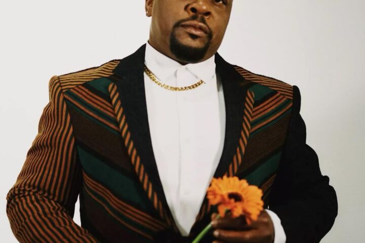 Kehinde Wiley in suit, holding flower.