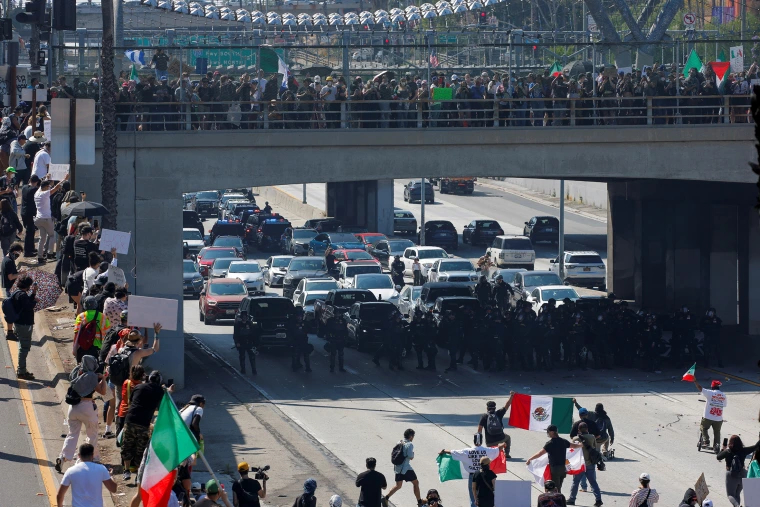 Demonstrators block the highway, as law enforcement officers stand facing them, during a protest against federal immigration sweeps in downtown Los Angeles, Calif., on Sunday. Mike Blake/REUTERS